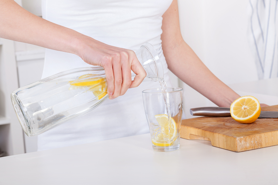 Young Woman Preparing And Drinking Lemonade In Her Kitchen